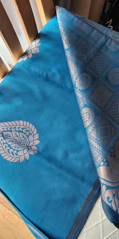 Blue soft silk saree with silver zari paisley motifs and geometric patterned pallu displayed with tassels
