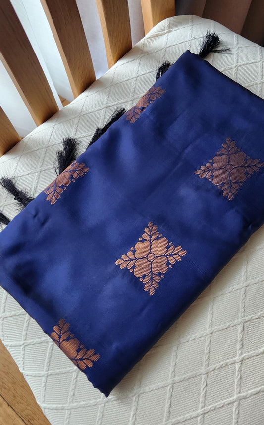 Navy blue soft silk saree with gold zari motifs, geometric woven border, and traditional pallu with tassels displayed on a light background.