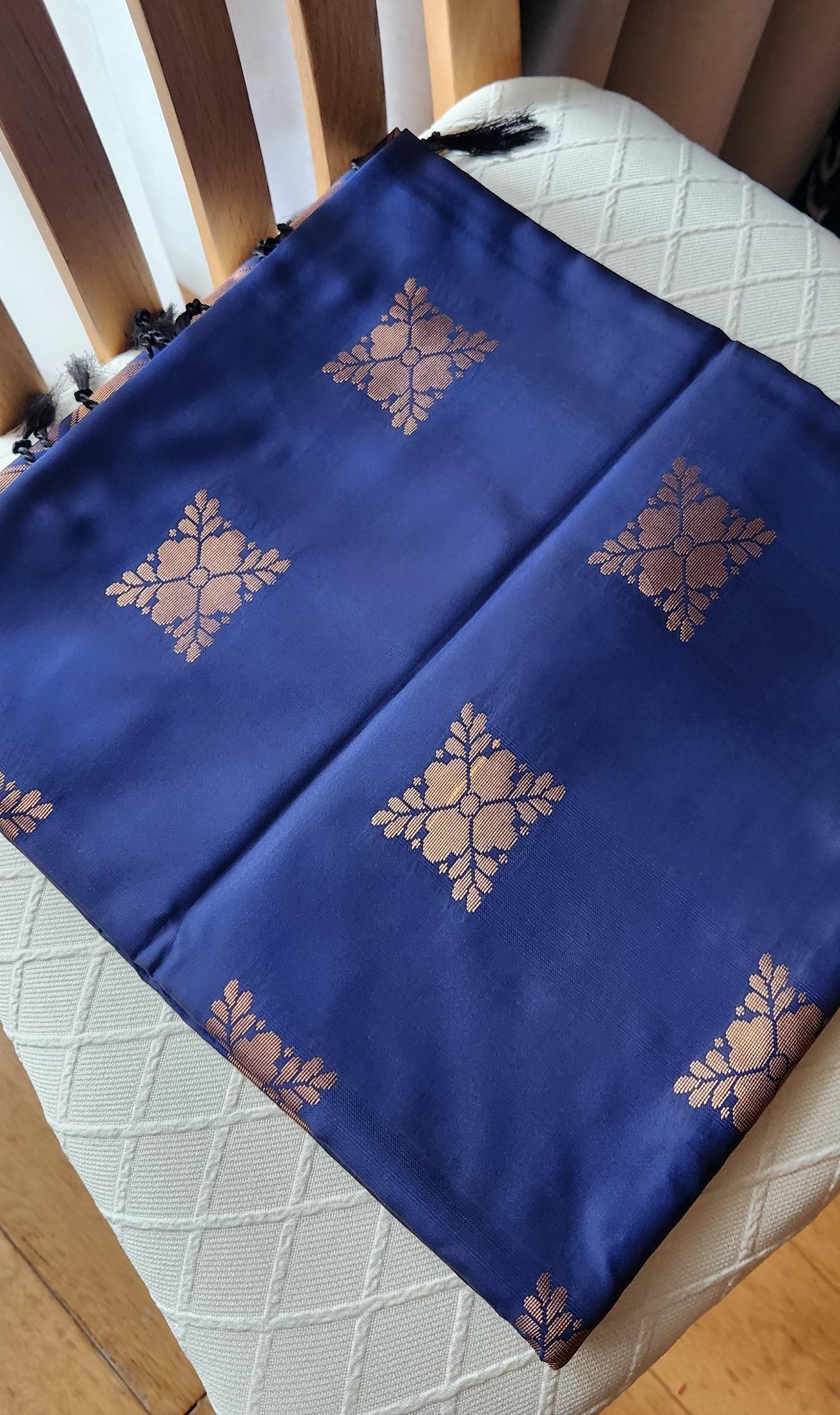 Navy blue soft silk saree with gold zari motifs, geometric woven border, and traditional pallu with tassels displayed on a light background.