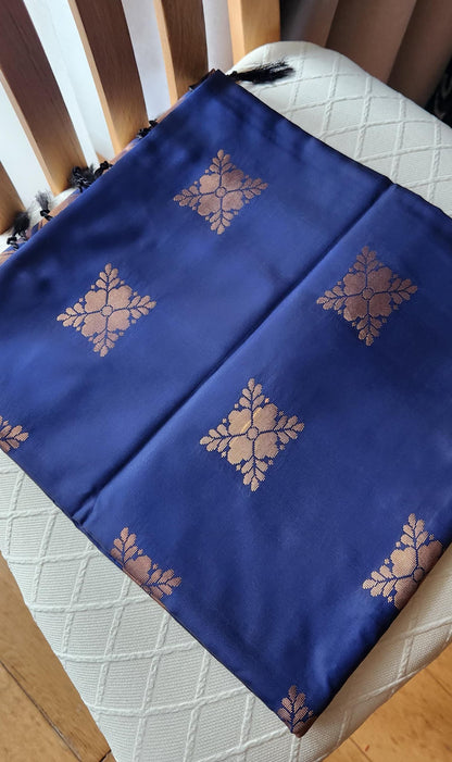 Navy blue soft silk saree with gold zari motifs, geometric woven border, and traditional pallu with tassels displayed on a light background.