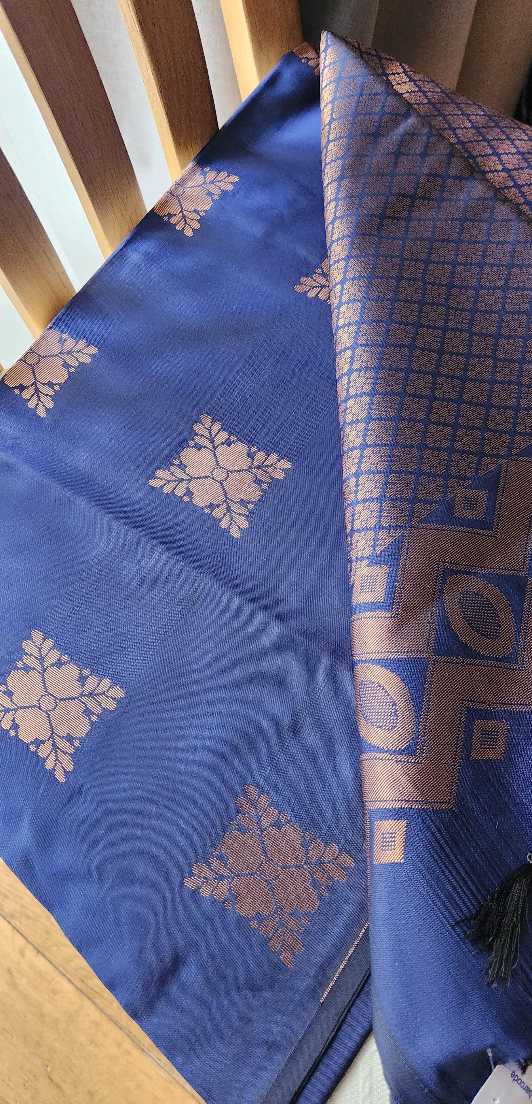 Navy blue soft silk saree with gold zari motifs, geometric woven border, and traditional pallu with tassels displayed on a light background.