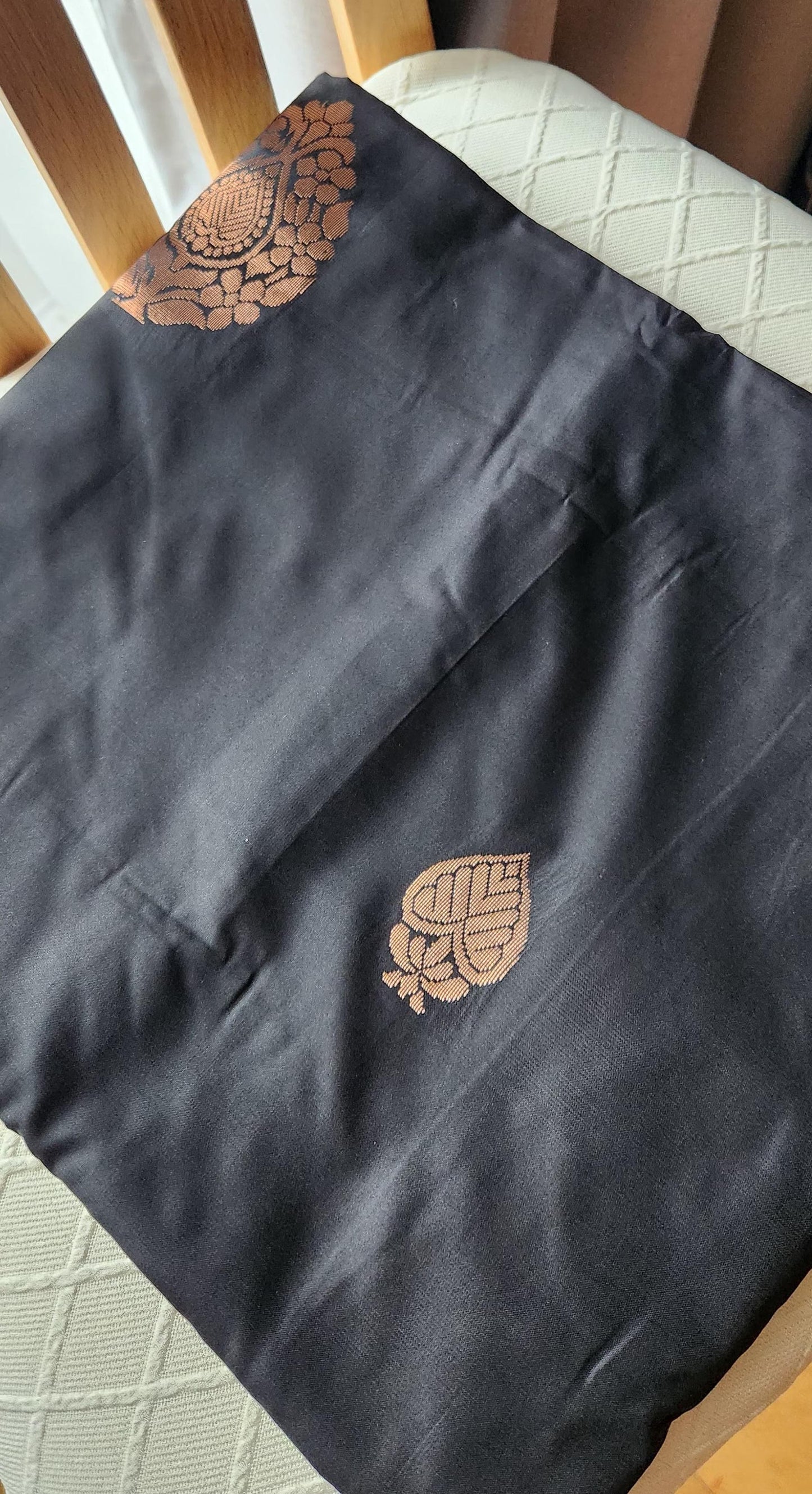 Charcoal black soft silk saree with antique copper zari motifs and traditional woven border displayed on a light fabric background