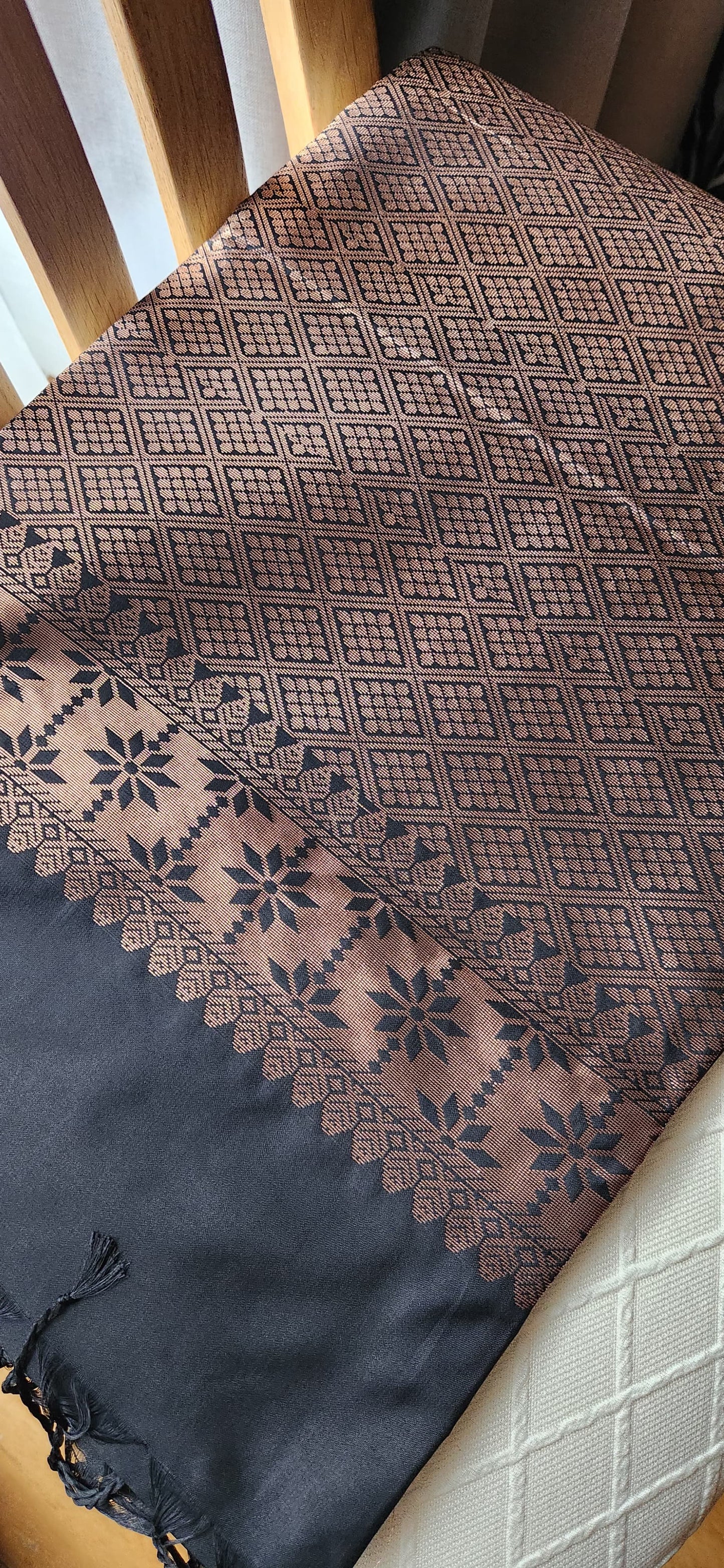 Charcoal black soft silk saree with antique copper zari motifs and traditional woven border displayed on a light fabric background