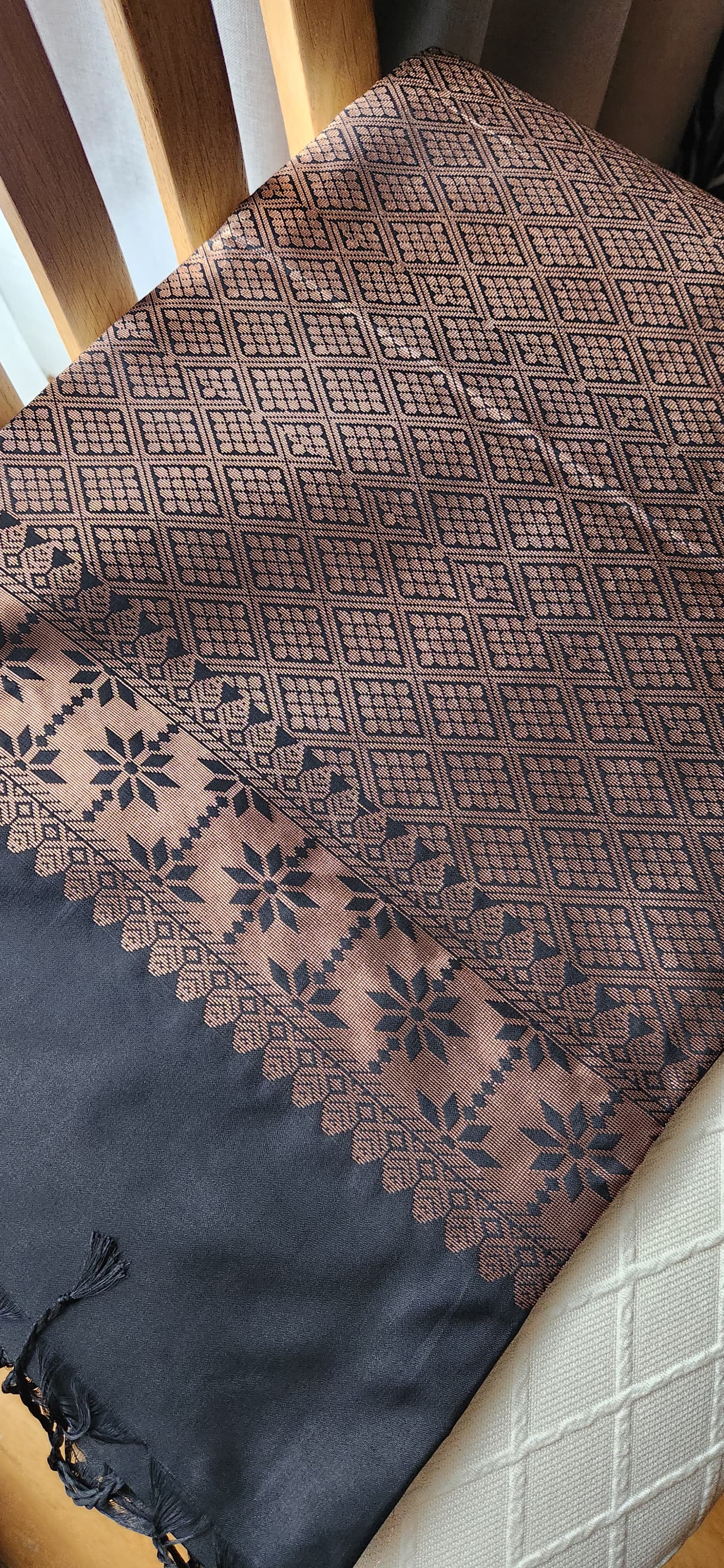 Charcoal black soft silk saree with antique copper zari motifs and traditional woven border displayed on a light fabric background