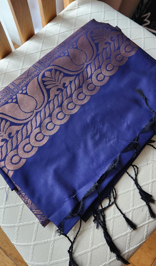 Deep navy blue silk saree with antique gold zari floral buttas and black tassels laid flat