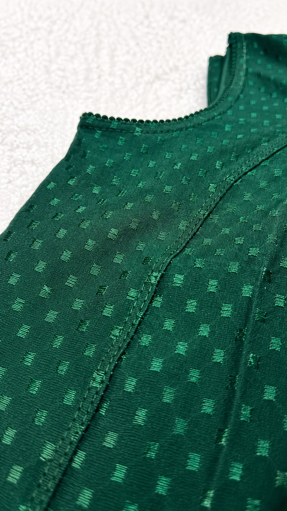 Close-up of a green textured fabric with a subtle pattern on a white background