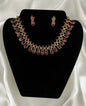 Antique gold ruby teardrop necklace and earrings jewelry set with Victorian style ornate metalwork displayed on black velvet stand