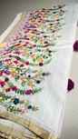 Off-white semi tussar silk saree with multicolor Resham thread embroidery, golden zari border, and maroon tassels.
