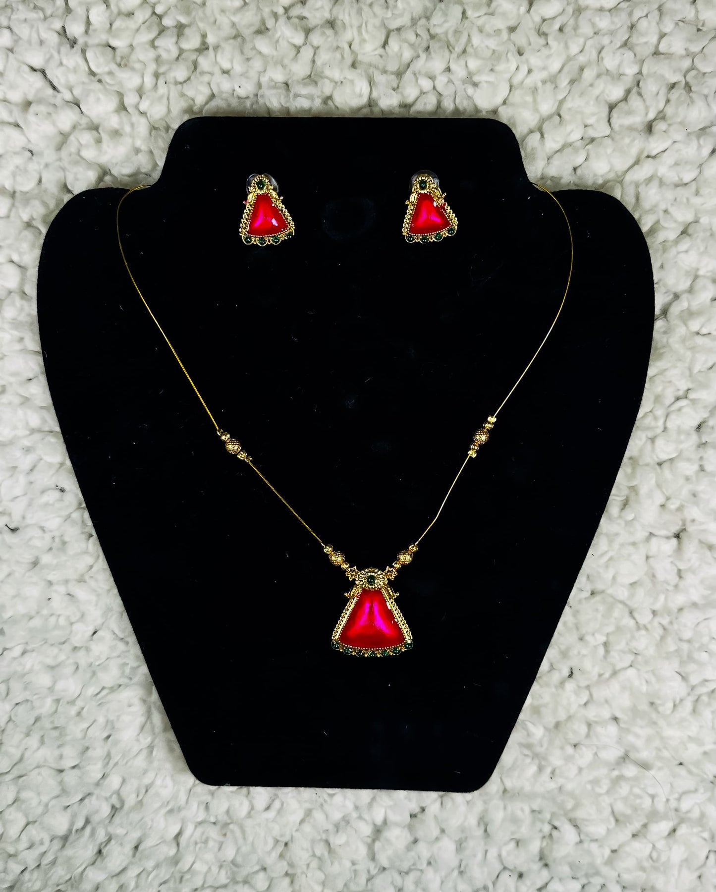 Gold triangle pendant necklace and earrings set with ruby red gemstone and ornate border detailing
