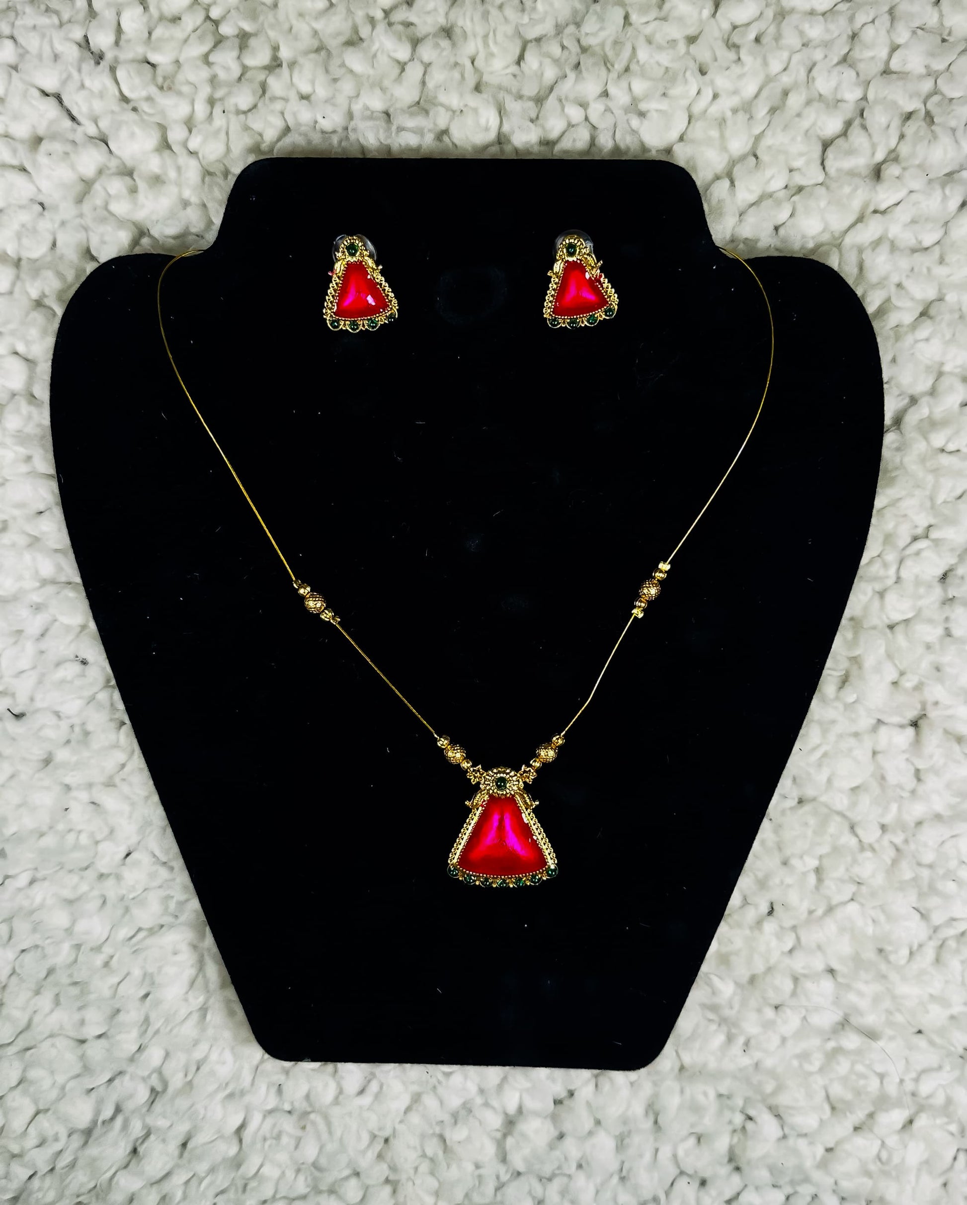 Gold triangle pendant necklace and earrings set with ruby red gemstone and ornate border detailing