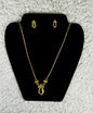 Gold plated geometric necklace and earrings jewelry set with emerald green diamond-shaped pendants displayed on black velvet jewelry stand