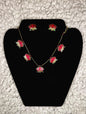 Red lotus flower jewelry set with gold-plated necklace and matching stud earrings displayed on black velvet jewelry display stand