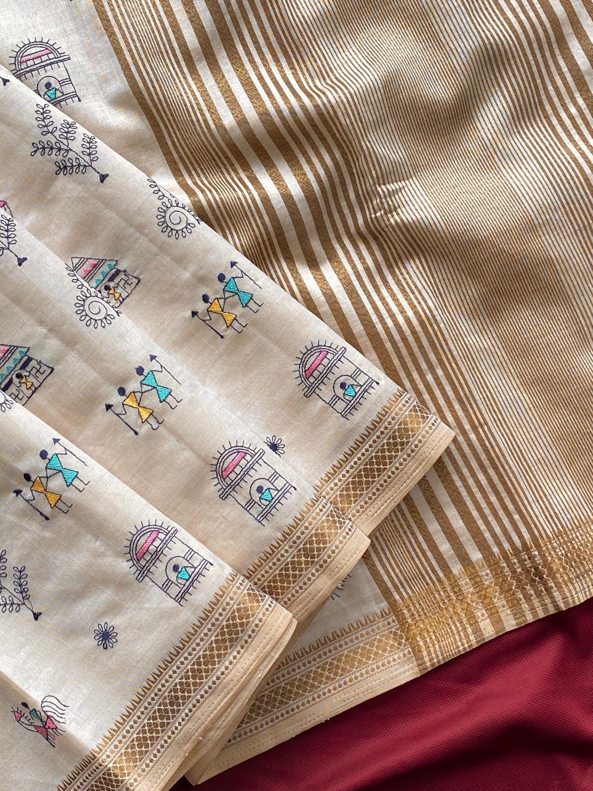 Pure tussar silk saree with all-over Worli embroidery, copper zari border, and zari woven pallu displayed flat.