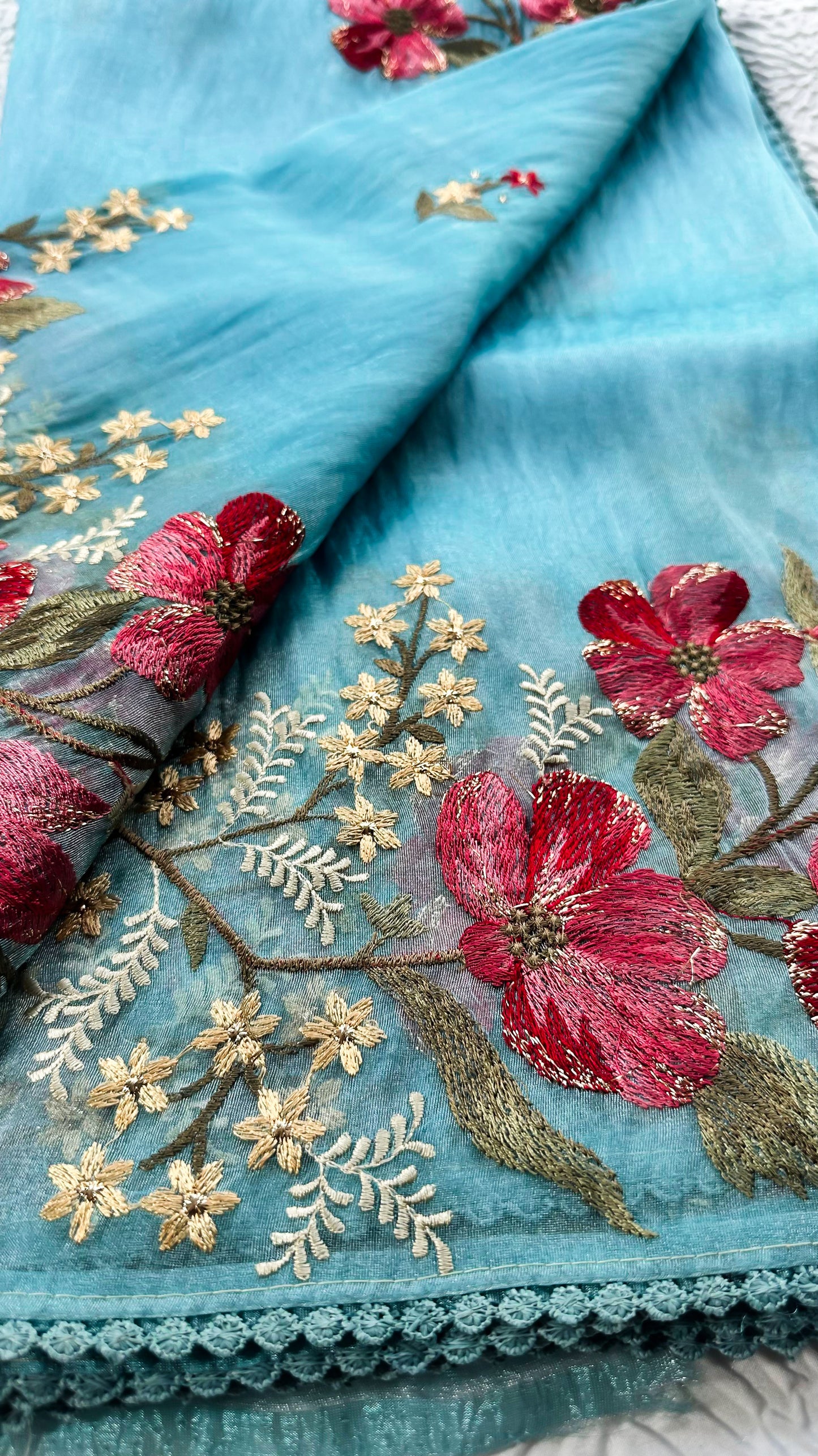 Teal blue glass tissue saree with multicolor Resham shaded floral embroidery and lace border.
