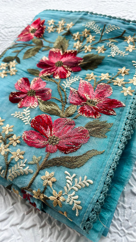Teal blue glass tissue saree with multicolor Resham shaded floral embroidery and lace border.
