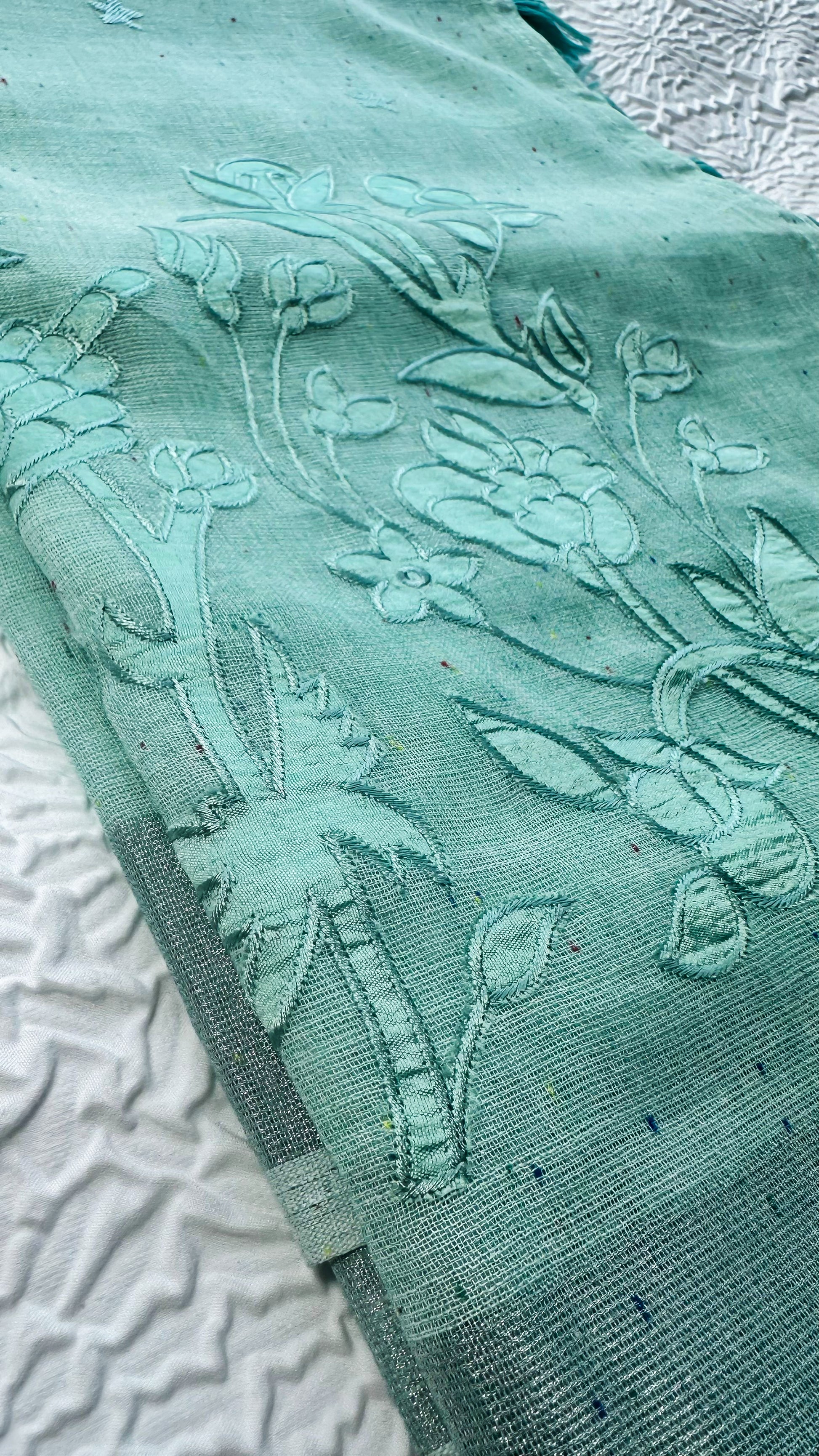Light blue linen saree featuring floral appliqué embroidery with tassel detailing on the pallu.