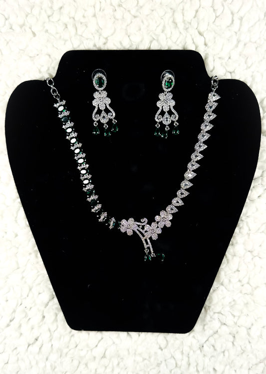Silver crystal rhinestone necklace and earrings jewelry set with emerald green accent stones displayed on black velvet stand