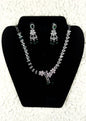 Silver crystal rhinestone necklace and earrings jewelry set with emerald green accent stones displayed on black velvet stand
