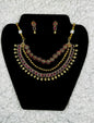 Traditional Indian bridal jewelry set with gold plated multi-layer necklace and ruby kundan earrings displayed on black velvet stand