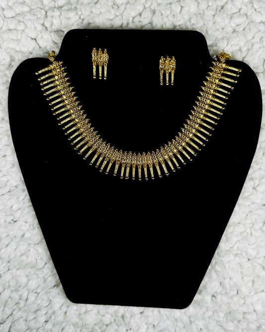 Traditional Indian gold fringe necklace and earrings jewelry set with cascading metal elements in tribal ethnic design displayed on black velvet stand