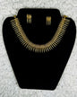 Traditional Indian gold fringe necklace and earrings jewelry set with cascading metal elements in tribal ethnic design displayed on black velvet stand