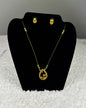 Traditional Indian gold thread necklace and earrings jewelry set with emerald green beads and paisley pendant showing authentic craftsmanship displayed on black velvet stand