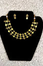 Traditional Indian multi-strand gold coin necklace and earrings jewelry set with temple motifs ruby accents and pearl details displayed on black velvet stand