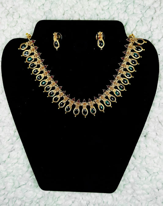 Traditional Indian gold paisley necklace and earrings jewelry set with multicolor kundan stones in collar design displayed on black velvet stand
