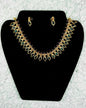 Traditional Indian gold paisley necklace and earrings jewelry set with multicolor kundan stones in collar design displayed on black velvet stand