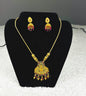Traditional Indian temple jewelry set with ornate gold Lakshmi pendant necklace and ruby jhumka earrings featuring goddess motifs and temple craftsmanship displayed on black velvet stand